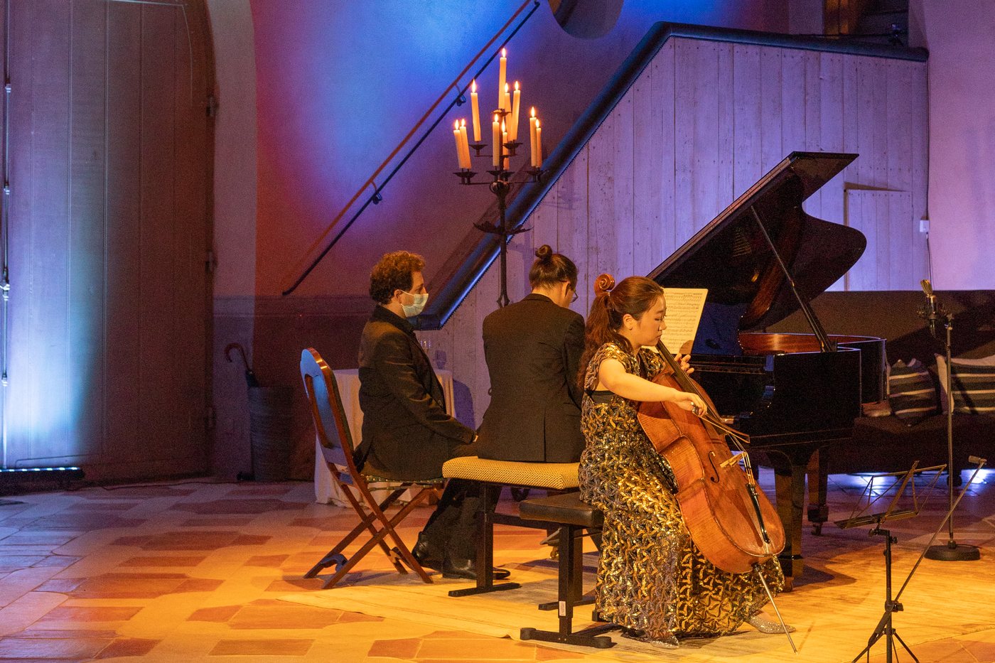 Another concert in the showroom: three musicians at the piano under the staircase, blue-violet light on the walls and amber light on the floor.